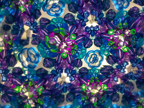 Ein symmetrisches Kaleidoskopmuster mit blauen, lila, grünen und weißen Formen.