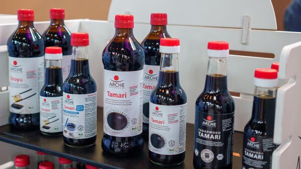 Messestand der ARCHE Naturküche mit ausgestellten Produkten in Regalen.