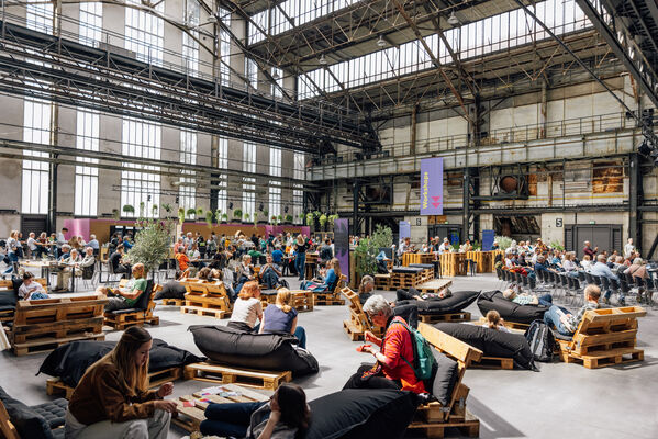 Menschen auf Palettenmöbeln in einer Industriehalle